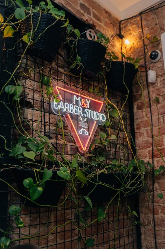 Рецепція M&Y Barber Studio: стійка, рослини, неонова вивіска